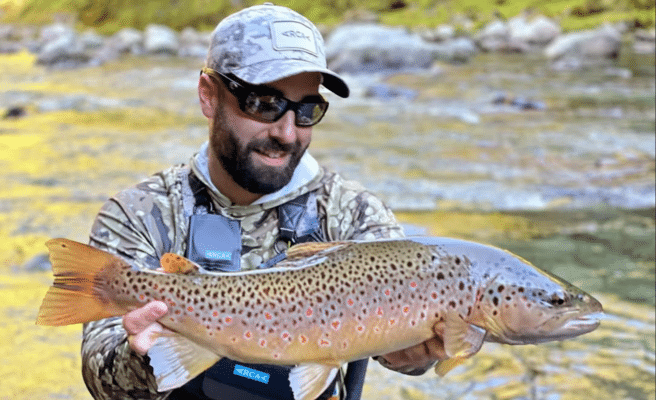 David Arcay, cinco veces campeón del mundo de pesca con mosca, sosteniendo una trucha marrón en un río español